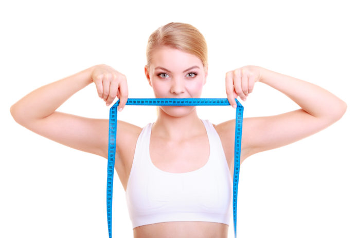 Fitness girl fit woman covering her mouth with measuring tape